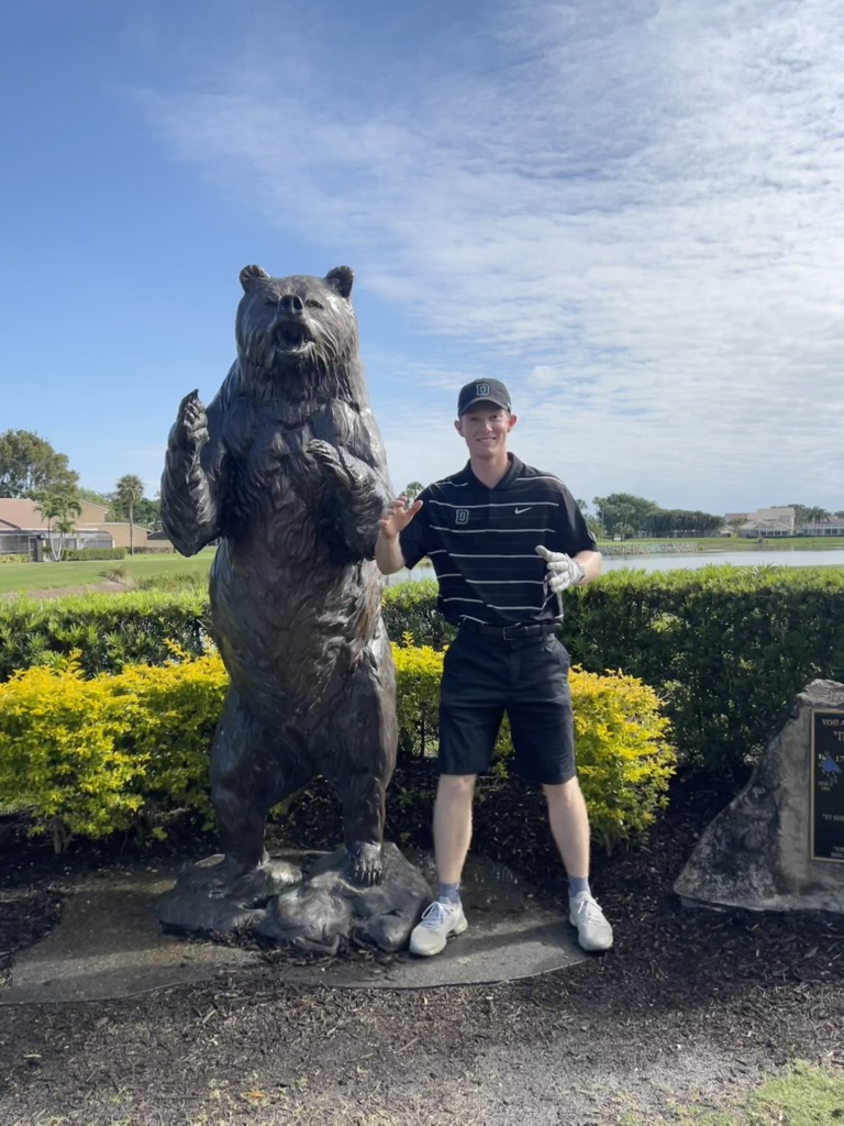 Cameron Keith at the bear statue on a golf course